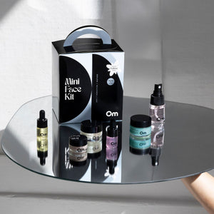 Mini face kit with various skincare products on a reflective surface from Om Organics