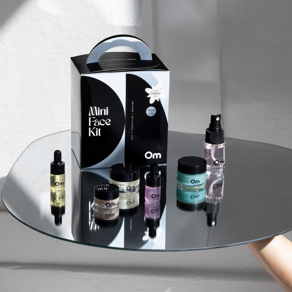 Mini face kit with various skincare products on a reflective surface from Om Organics