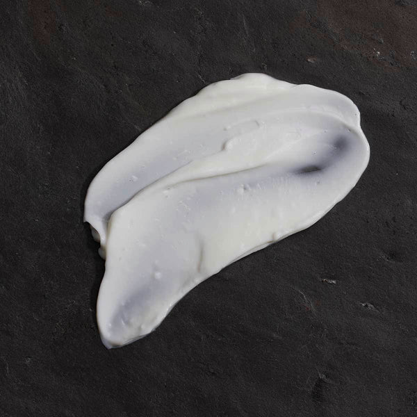 A swatch of white OM ORGANICS Rosewood + Vanilla Rich Hydration Hand Cream on dark background