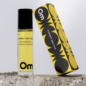 Yellow and black scented roll-on perfume bottle with packaging on a stone surface.