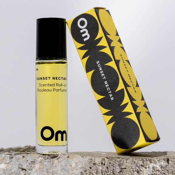 Yellow and black scented roll-on perfume bottle with packaging on a stone surface.