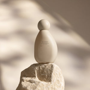 Beige bottle labeled 'RAESO' on a rock with a blurred natural background