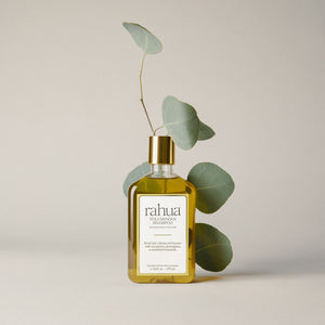 Bottle of rahua voluminous shampoo with eucalyptus leaves on a neutral background. full size