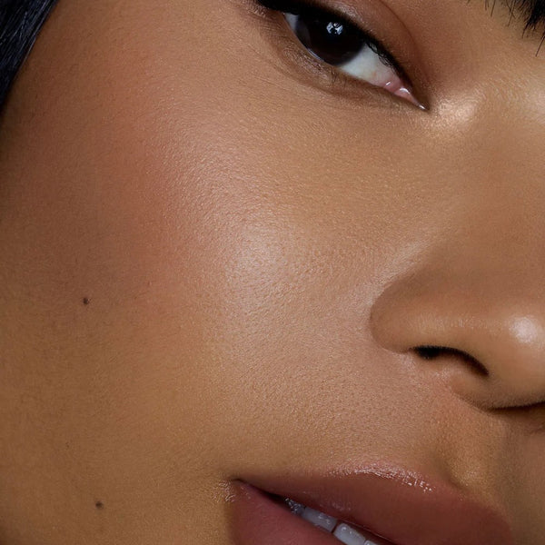 Close-up of a person's face with a focus on the skin texture. RITUEL DE FILLE Color Nectar Pigment Balm Ghost Flower