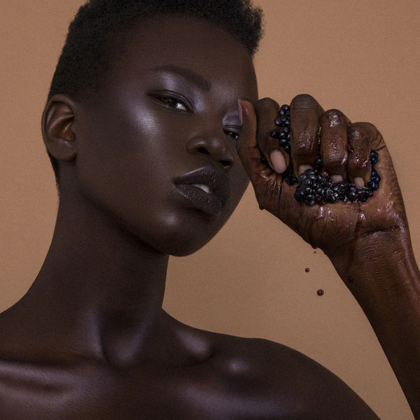 Woman holding blackberries with a brown background. RITUEL DE FILLE Inner Glow Crème Pigment Eclipse
