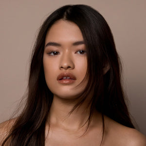 Woman with long dark hair against a neutral background. RITUEL DE FILLE Inner Glow Crème Pigment Eros