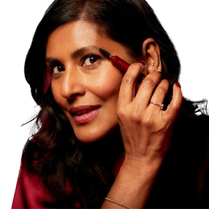 Woman using Ruby Hammer spoolie brush on her brows with a white background