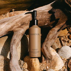 SANDOR bottle of conditioner with a black pump on a natural background with wood and stones ALWAYS SHOW