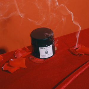 Black jar with a label on a red surface with smoke effect