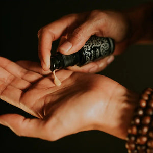 Woman holding a black bottle with a pump and applying a small amount of SIAM SEAS Sai Clear Skin Vitamin C Serum to their palm