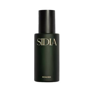 SOAKED Body Mist in a minimalist dark green bottle, a lightweight hydrating fragrance mist with lemon, grapefruit, amber, and skin-supporting ingredients.