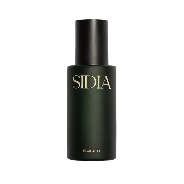 SOAKED Body Mist in a minimalist dark green bottle, a lightweight hydrating fragrance mist with lemon, grapefruit, amber, and skin-supporting ingredients.