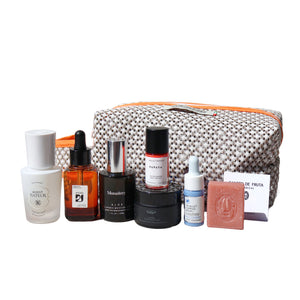 Collection of skincare and cosmetic products with a patterned pouch on a white background