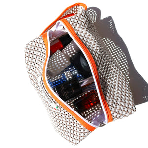 Mesh pouch with orange zipper containing various items on a white background