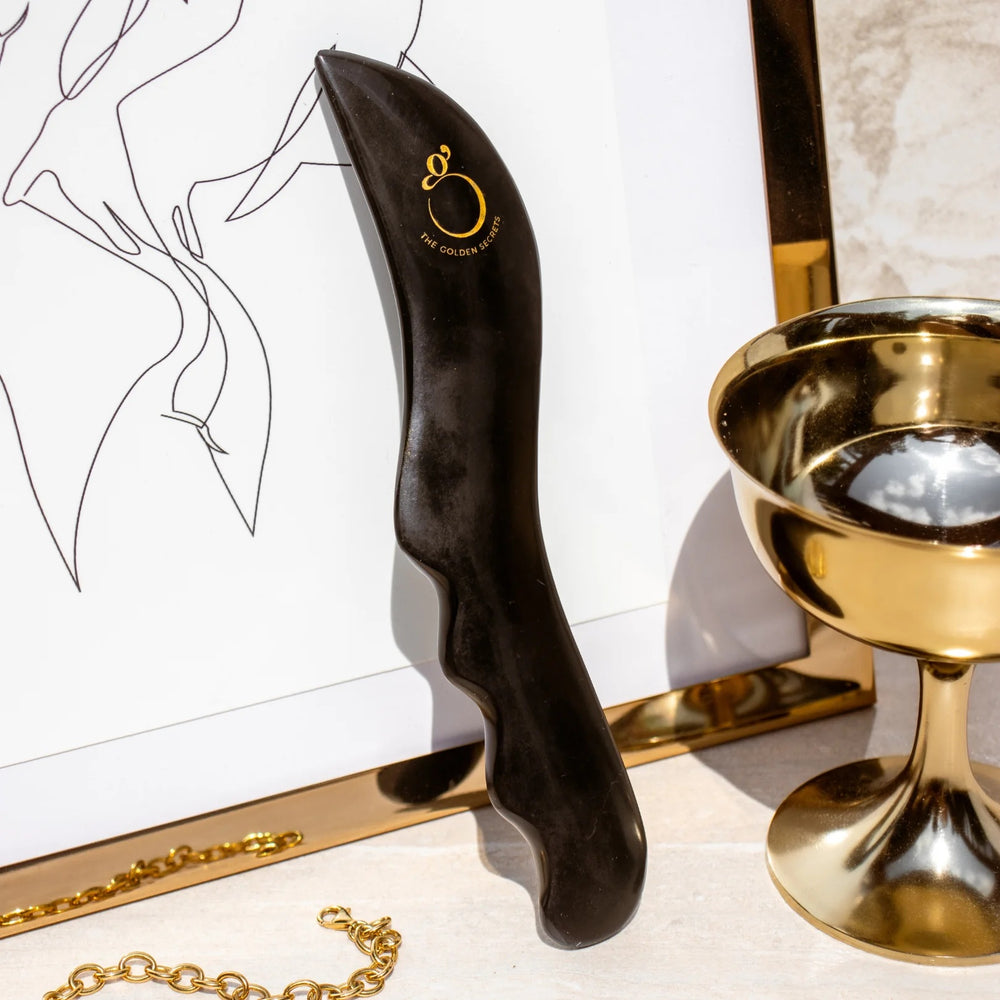 The Golden Secrets Sculpting Stone Gua Sha Body Tool made from Sibin Bian stone with unique properties like Far Infra-Red waves and ultrasonic pulses, designed to elevate your beauty ritual.