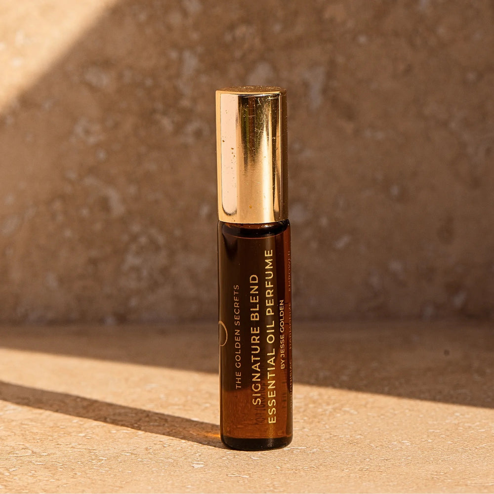 The Golden Secrets Signature Blend Essential Oil Perfume, a high vibrational, organic perfume with a unique scent crafted from jasmine, lemon, patchouli, lavender, sandalwood, and jojoba oil. This aphrodisiac blend harmonizes and empowers the wearer, creating an alluring fragrance that adapts to your body chemistry. The refreshing and uplifting scent is ideal for daily use and travel, helping to entice romance and abundance. EWG and Think Dirty Verified, with 94% organic content. 5 ml bottle.