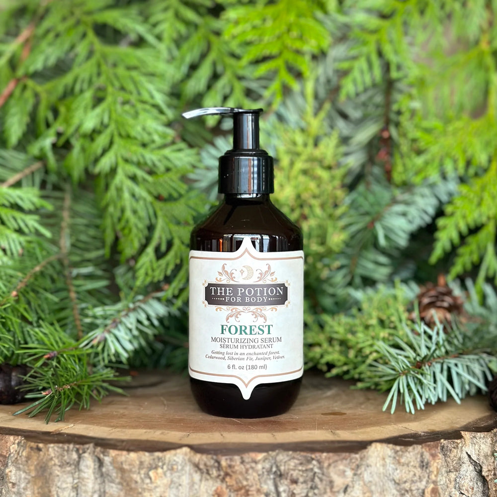 The Potion Cosmetics Forest Body Potion bottle on a natural wood surrounded by pine branches