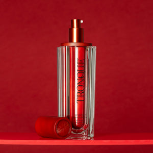 Red skincare bottle with pump on a red background. TRONQUE Exfoliating Refining Serum