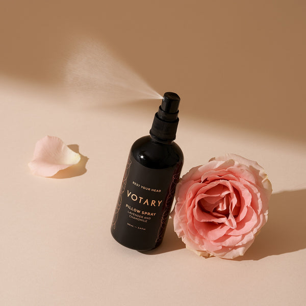 Black spray bottle labeled 'Votary' with a pink rose on a beige background