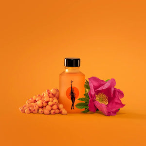 Orange bottle of Wonder Valley Face Oil with black cap, berries, and pink flower on an orange background