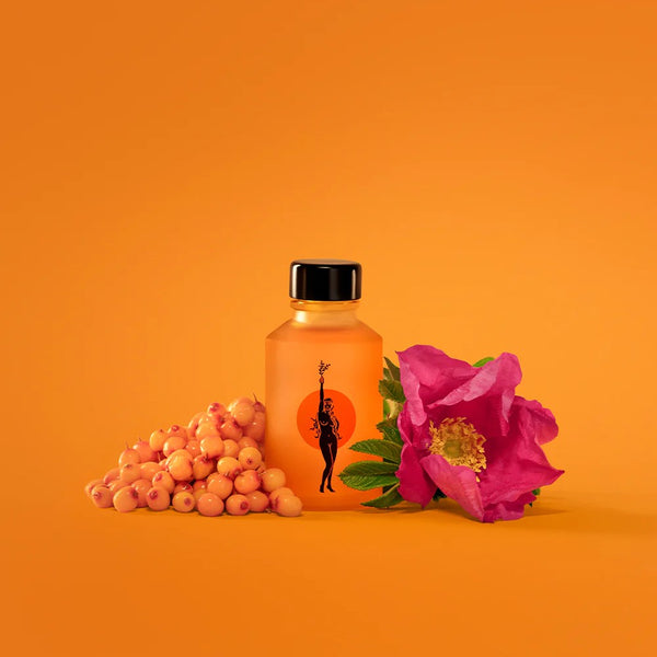 Orange bottle of Wonder Valley Face Oil with black cap, berries, and pink flower on an orange background