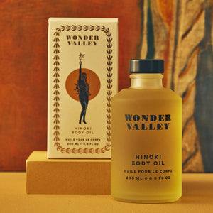 Wonder Valley Hinoki Body Oil bottle and packaging on a warm-toned background