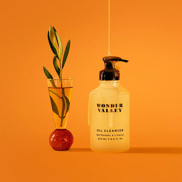 Oil cleanser bottle by Wonder Valley with olive branch on an orange background