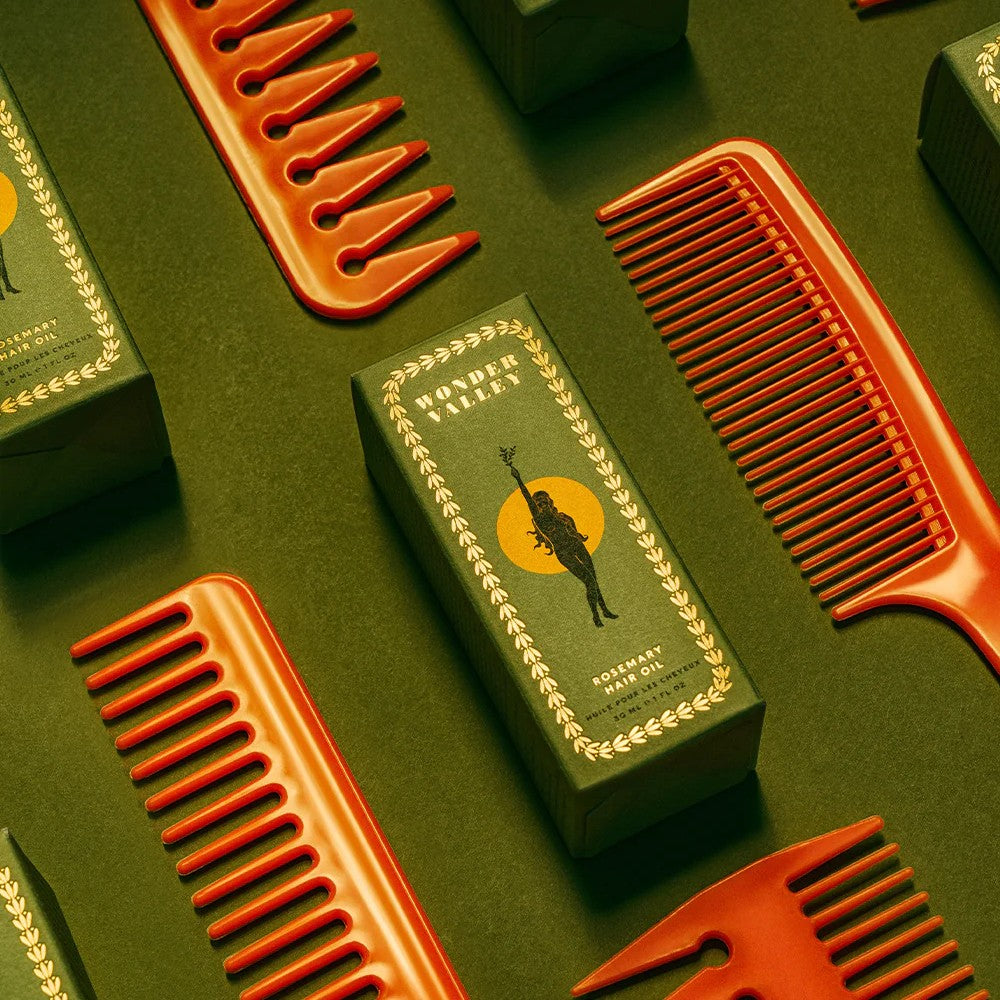 Clear glass bottle and green box of Wonder Valley hair oil on a white background