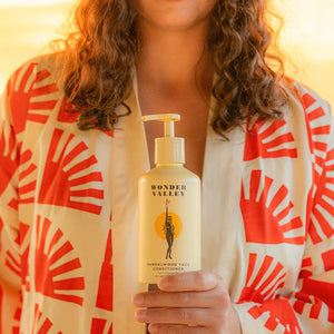 Person holding a bottle of Wonder Valley conditioner with a warm glow