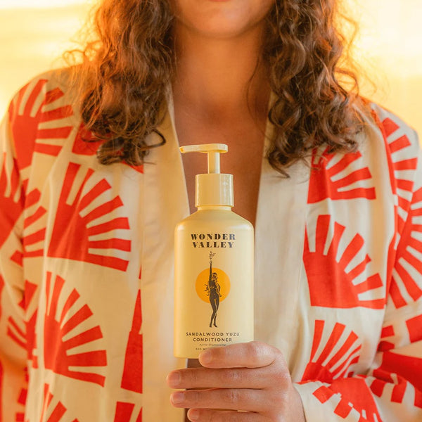 Person holding a bottle of Wonder Valley conditioner with a warm glow