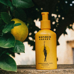 Yellow shampoo aluminium bottle with 'Wonder Valley' branding next to a lemon and leaves